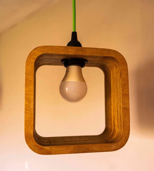 Single Bulb Halo Pendant Light made of layered birch plywood with a smooth finish, suspended by a yellow fabric cable.